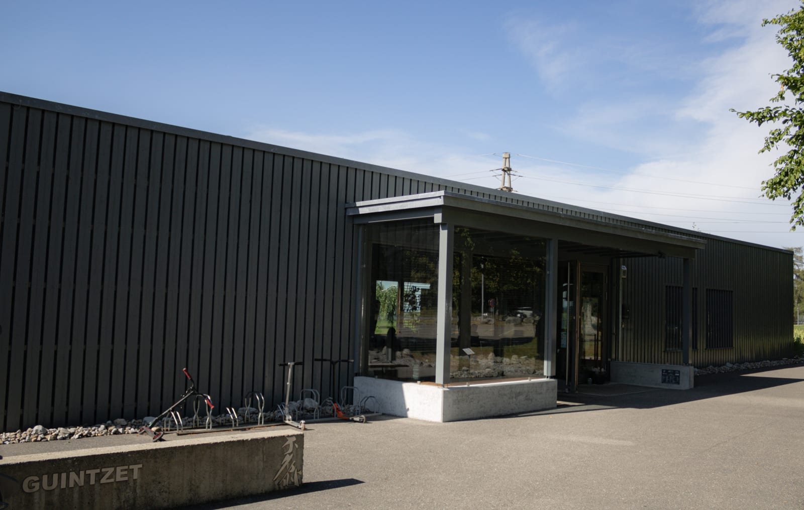 Façade en bois sombre du bâtiment de Villars-sur-Glâne avec véranda vitrée