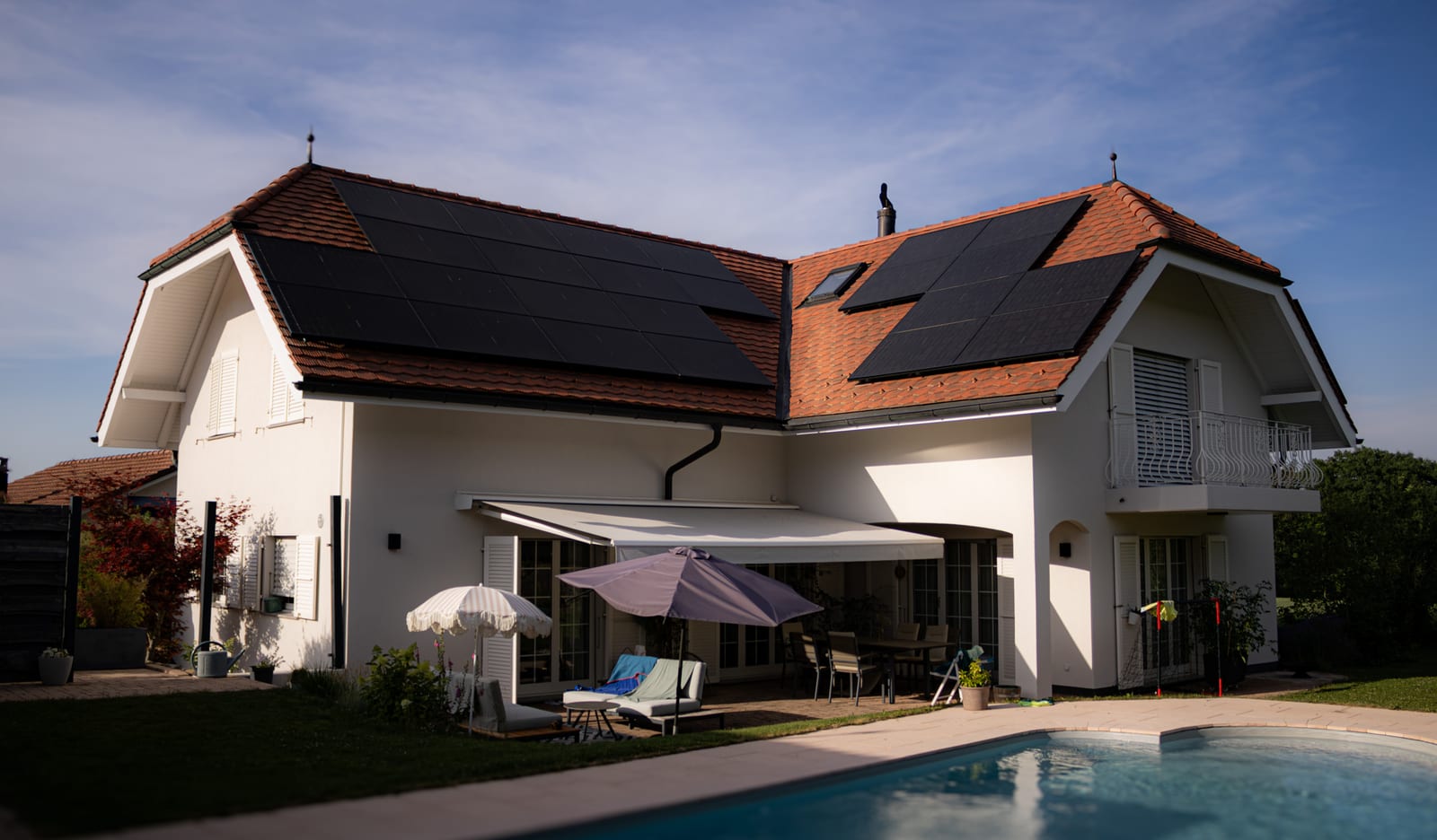 Villa rénovée par Ambicolor à Ependes, façade claire côté piscine avec terrasse et panneaux solaires