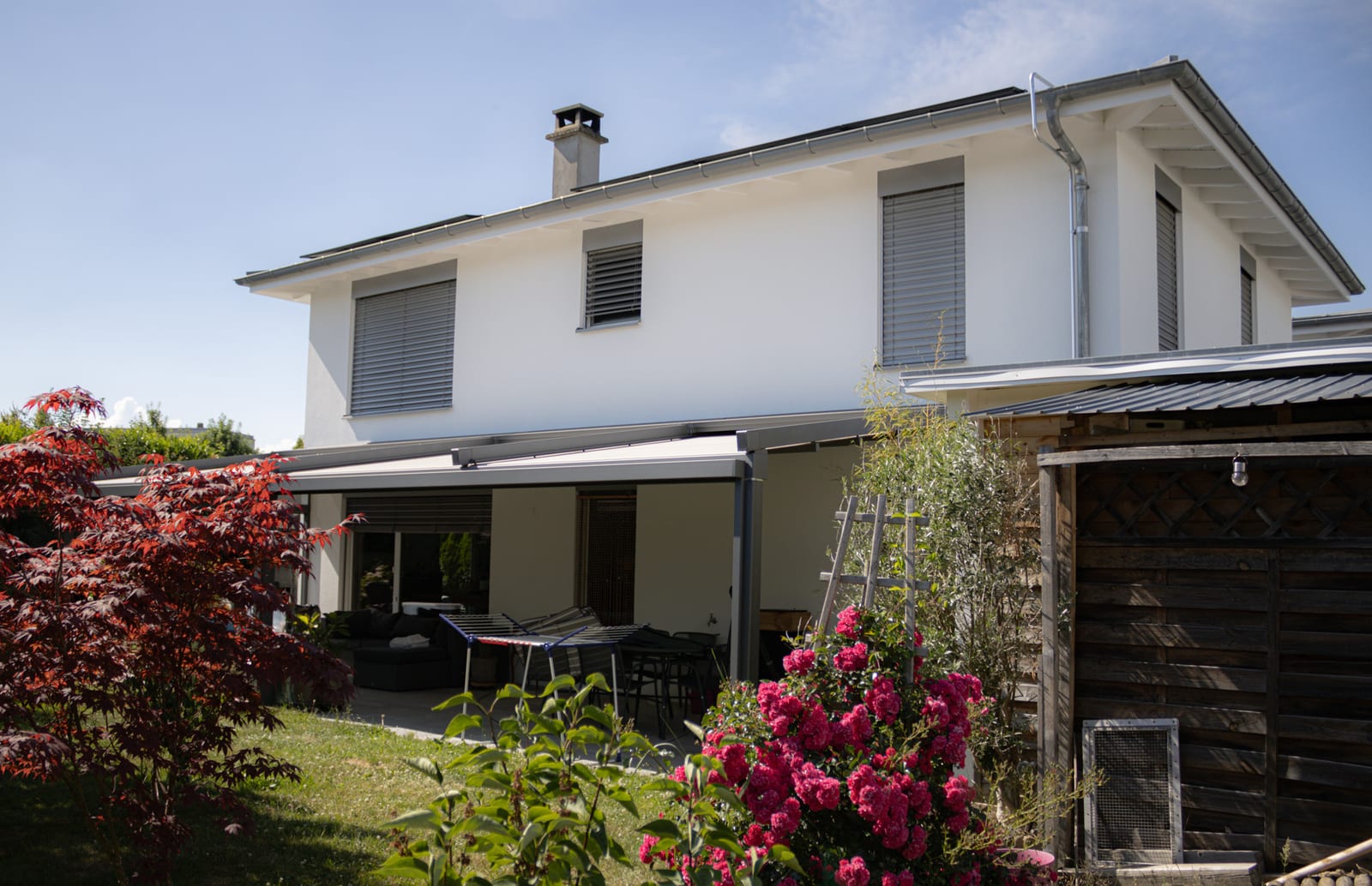 Façade de la maison de Neyruz côté jardin, avec store banne