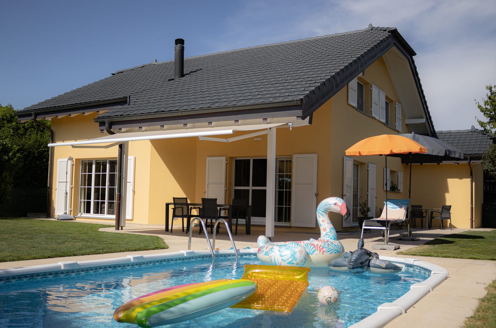 Façade d'Avry-sur-Matran côté piscine, avec terrasse et avant-toit repeint